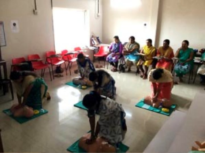 Participants kneeling beside manikins practising chest compressions
